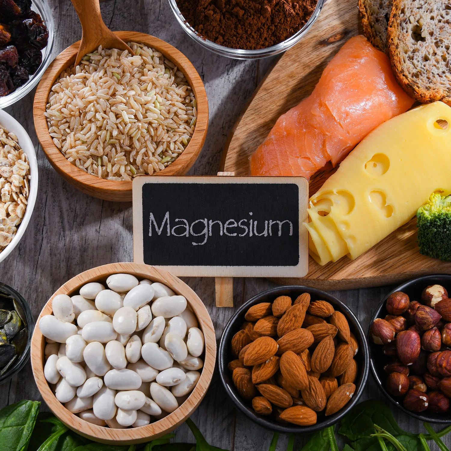 In der Mitte befindet sich eine Tafel mit der Aufschrift 'Magnesium', umgeben von magnesiumhaltigen Lebensmitteln wie Nüssen.