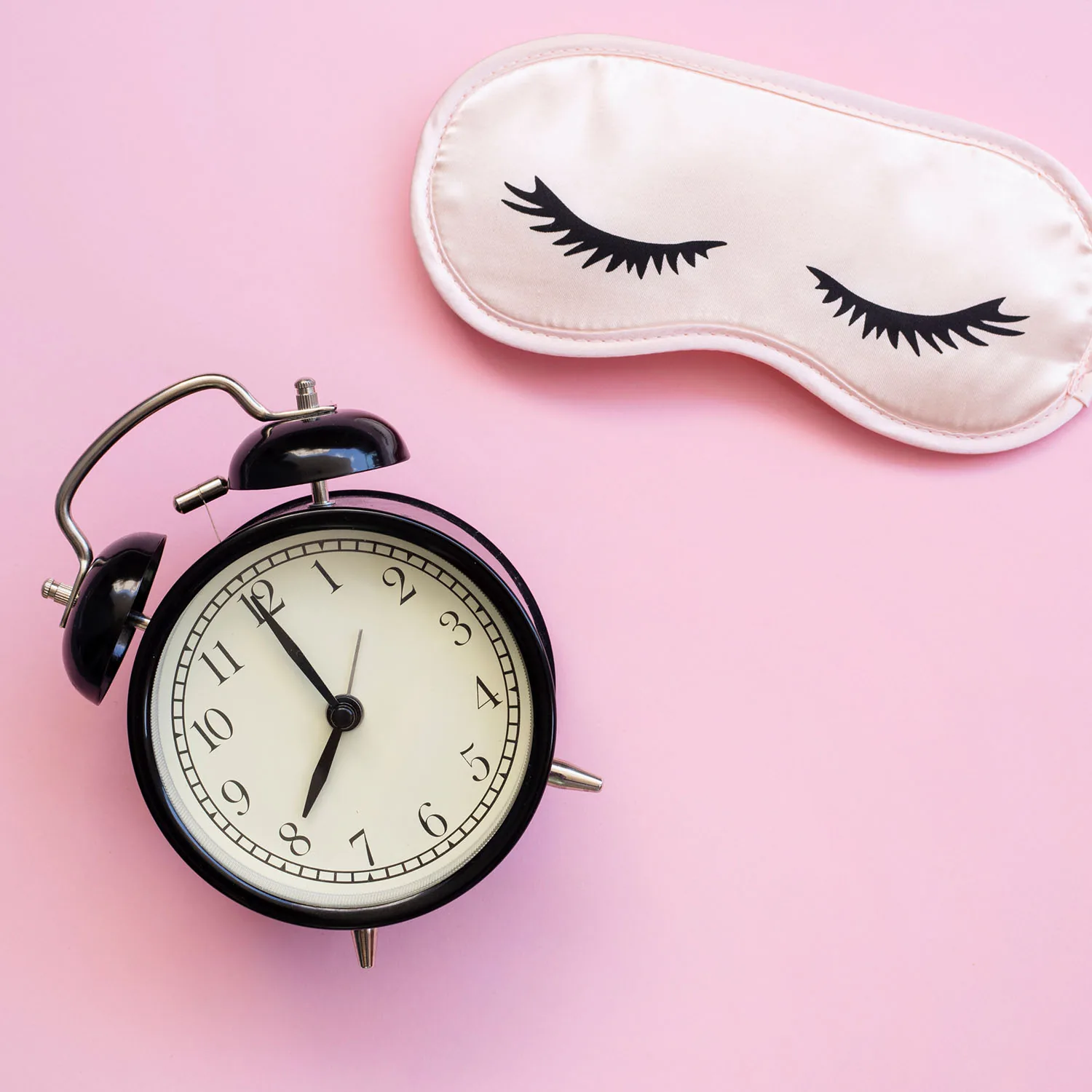 Es ist ein Wecker zu sehen, der 8 Uhr anzeigt, sowie eine Schlafmaske.